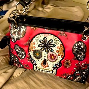 Cute pink purse with sugar skulls and pretty floral decorations.